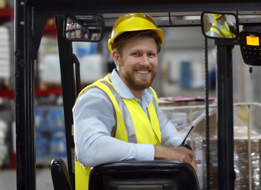 male warehouse worker sitting in forklift truck