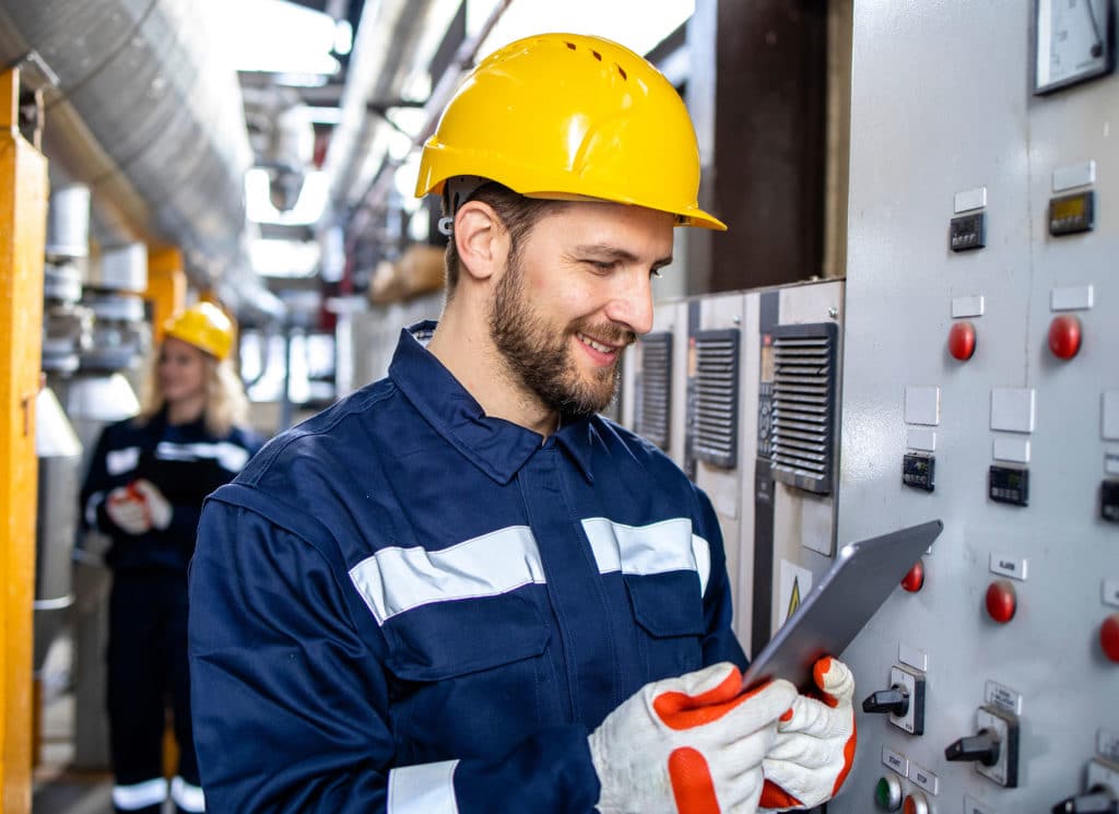 Industrial electrician in safety work wear checking power consumption